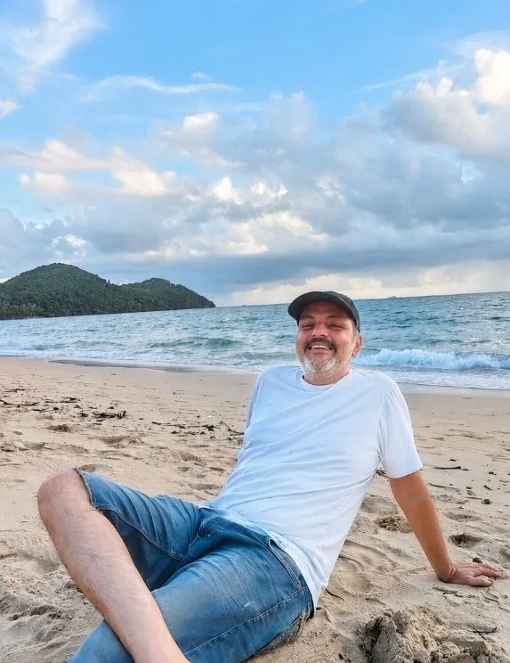 AB smiling while sitting on a beach